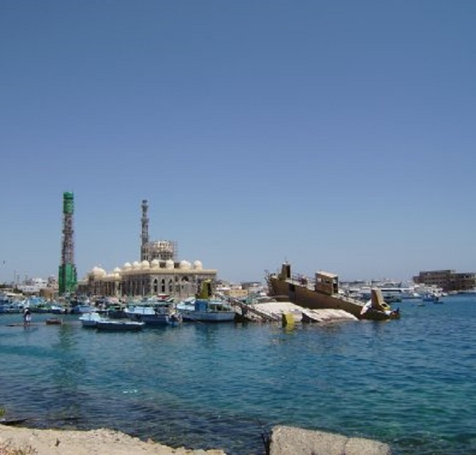 Vissershaventje naast de marina. Er ligt een afgezonken pontveer. Op de achtergrond de nieuwe, grote moskee in aanbouw