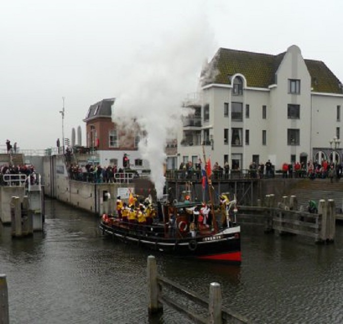Sinterklaas vaart de sluis uit. Erachter staat ons huis met beneden het te lichte vlak voor het gedicht van de Poëzieroute.