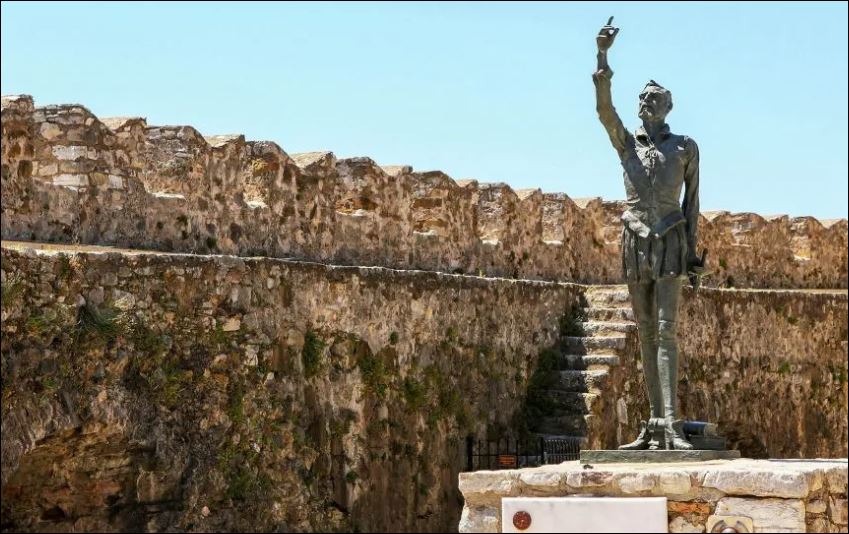 Beeld van Miguel de Cervantes op een bastion in Nafpaktos. Zijn verlamde linkerarm hangt af langs zijn lichaam, maar fier heft hij zijn pen in de rechterhand