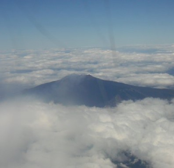 Na het opstijgen maakt het vliegtuig een grote bocht om de vulkaan Etna. De top steekt een eind boven de wolken uit. Zie de rook, die de kraters uitbraken