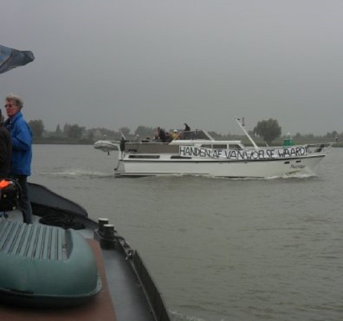 Motorkruiser 'Hunter' op de rivier met het protestdoek 'Handen af van de Woelse Waard'