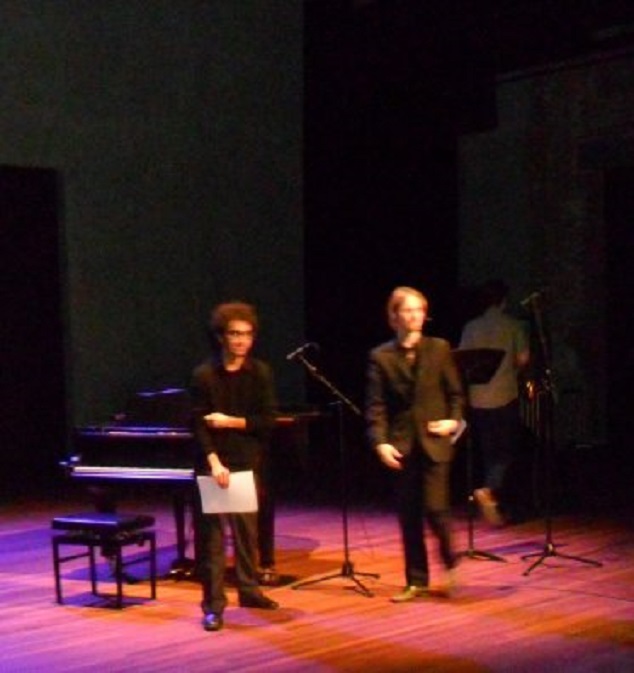 Bas loopt het toneel op om de musici te bedanken en het applaus in ontvangst te nemen. Links pianist Renán Zelada. Saxofist Daan van Koppen (rechts) loopt juist weg