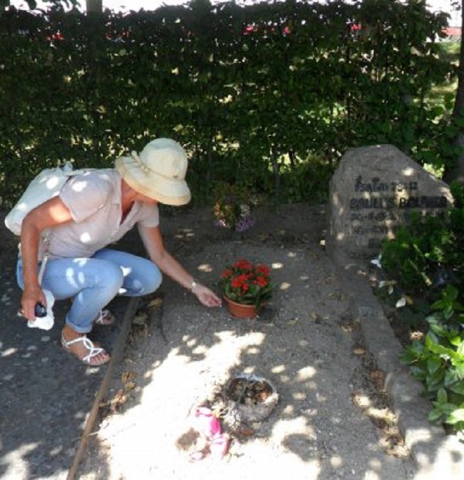 Ans zet bloemen op het graf van haar ouders.