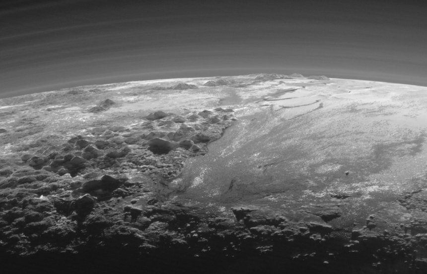 De dwergplaneet Pluto, recente foto van de sonde New Horizons. Links een gebergte, recht Sputnik Planum. Bron: NASA