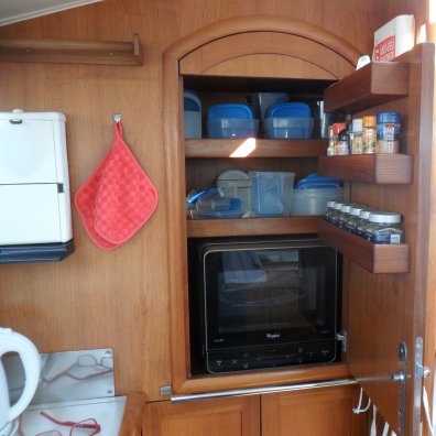 De nieuwe magnetron op zijn plaats in de kombuiskast. De lijst zit er weer op, de handdoekenstang en het kastdeurtje is alweer aangebracht. De houder van de scheepstoeter zit achter het deurtje, die zie je niet.
