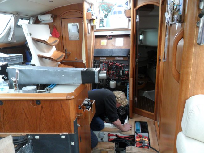 Op het keukenblok ligt het nieuwe waterslot/uitlaatdemper, keurig voorzien van isolatievellen, ingetaped met ducktape. Fons bereid de plaatsing in de bakboord motorsteun voor.