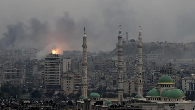 Recente foto van het centrum van Aleppo met de beroemde citadel op de achtergrond. Links slaat een vliegtuigbom in. Op de voorgrond de onbeschadigde moskee van Assad.