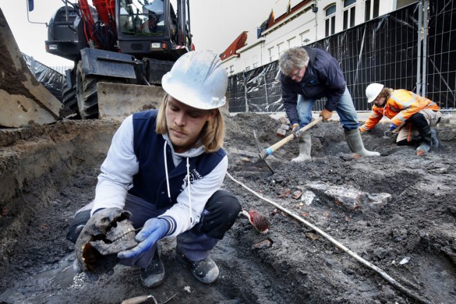 Een archeoloog houdt een schedel in de hand, gevonden naast de kerk. (foto: Cor de Cock)