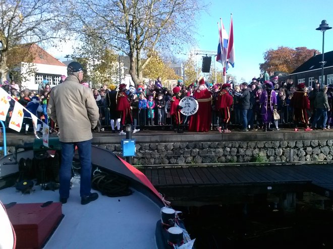 Lourens kijkt in Veghel op de voorplecht van 'Niets Zonder Gods Zegen'  naar de Sint op de kade.