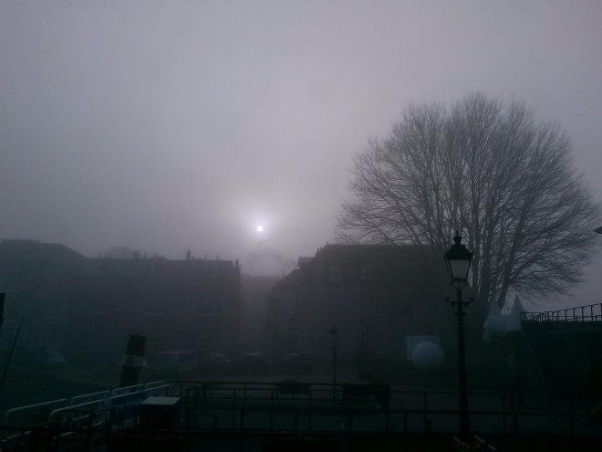 Vanochtend is het mistig. Boven de daken van de huizen aan de Kriekenmarkt poogt de zon erdoor te komen.