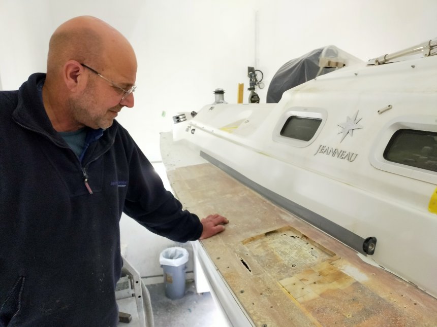 Benno toont een vierkant stukje van het dek waar de laag balsablokjes is weggehaald. Gaten en schuren in het glasvezel van de glasvezel-onderlaag. Geen wonder dat het lekt.