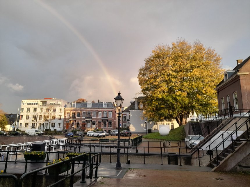 Rechts de esdoorn bij de Kriekenmarkt in herfsttooi en links een toevallige regenboog. De pot met goud staat op het dak van het appartementencomplex aan het Nonnenveld.
